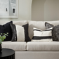 White sofa with black and white patterned cushions in a living room setting.
