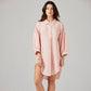 Woman wearing a pink striped nightshirt on a plain background