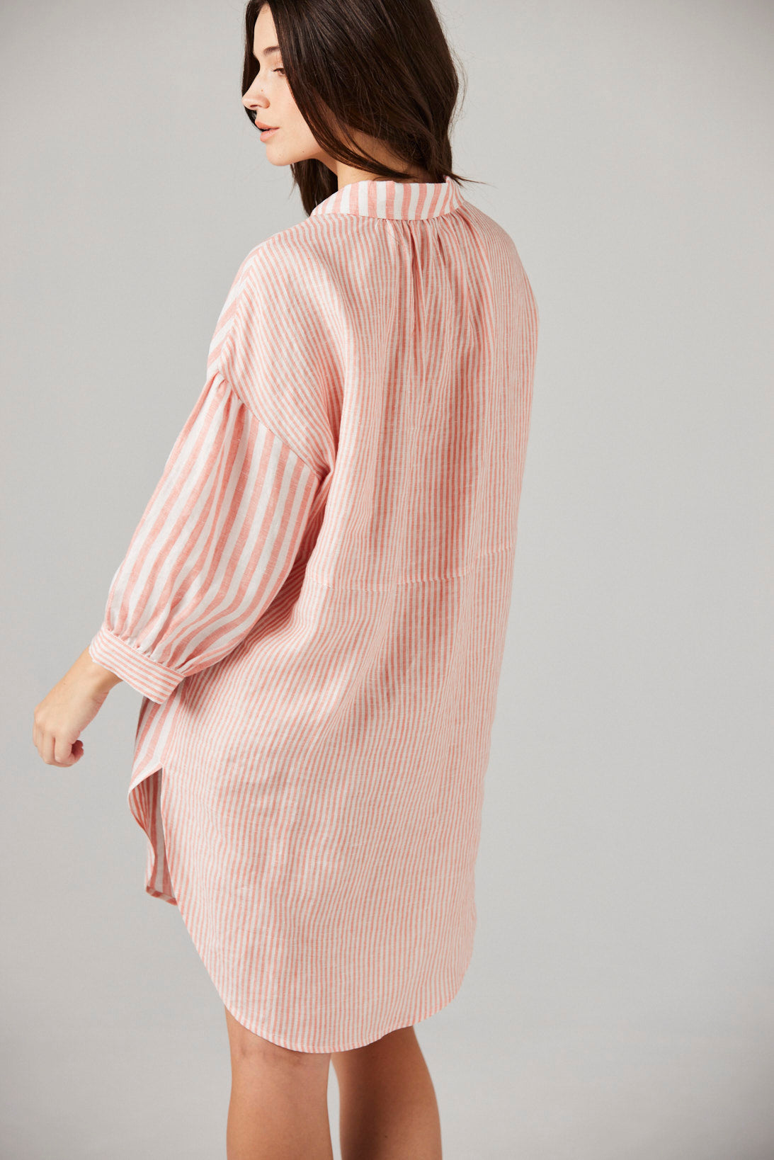Woman wearing a pink striped night shirt against a gray background