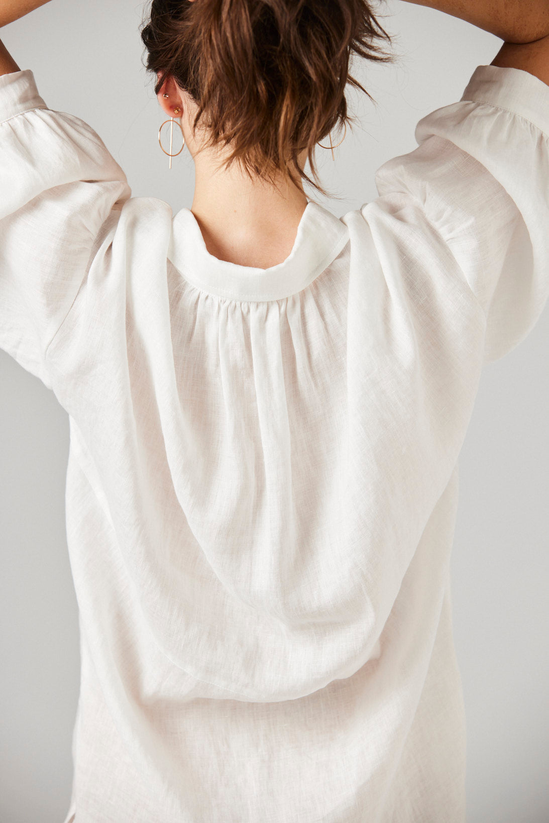 White blouse with puffed sleeves worn by a person against a plain background