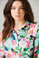 Woman wearing a colorful floral shirt against a plain background