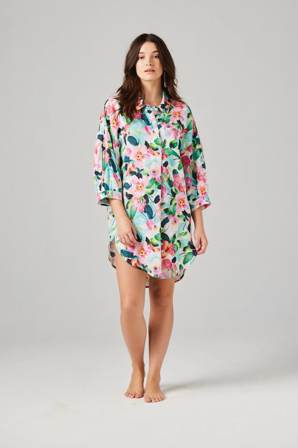 Woman wearing a colorful floral linen night shirt on a gray background