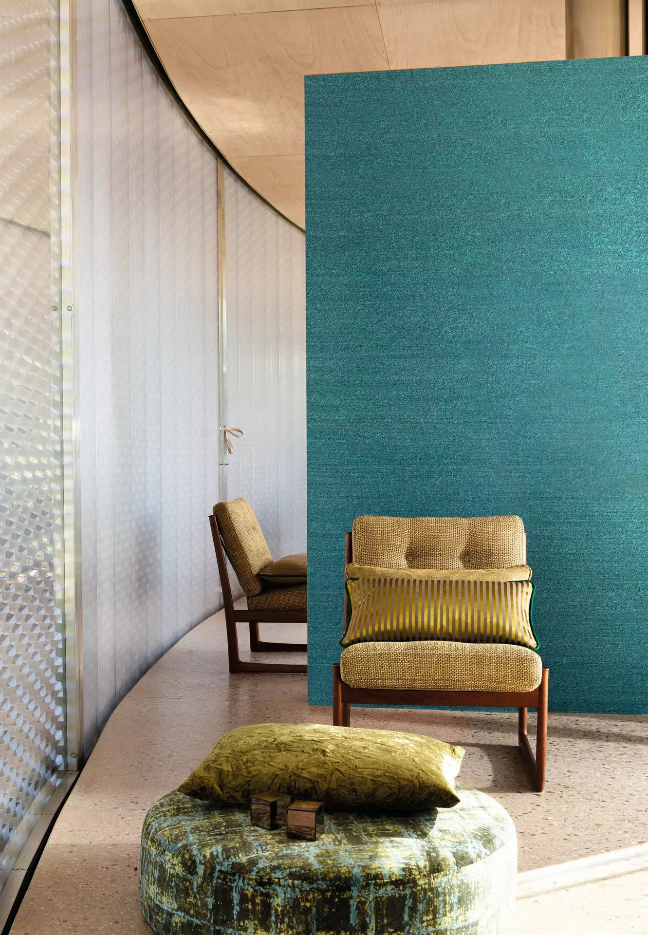 Modern interior with a green upholstered chair and ottoman against a teal wall.