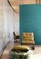 Modern interior with a green upholstered chair and ottoman against a teal wall.