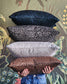 Four patterned pillows stacked with a person holding the bottom one against a decorative background.