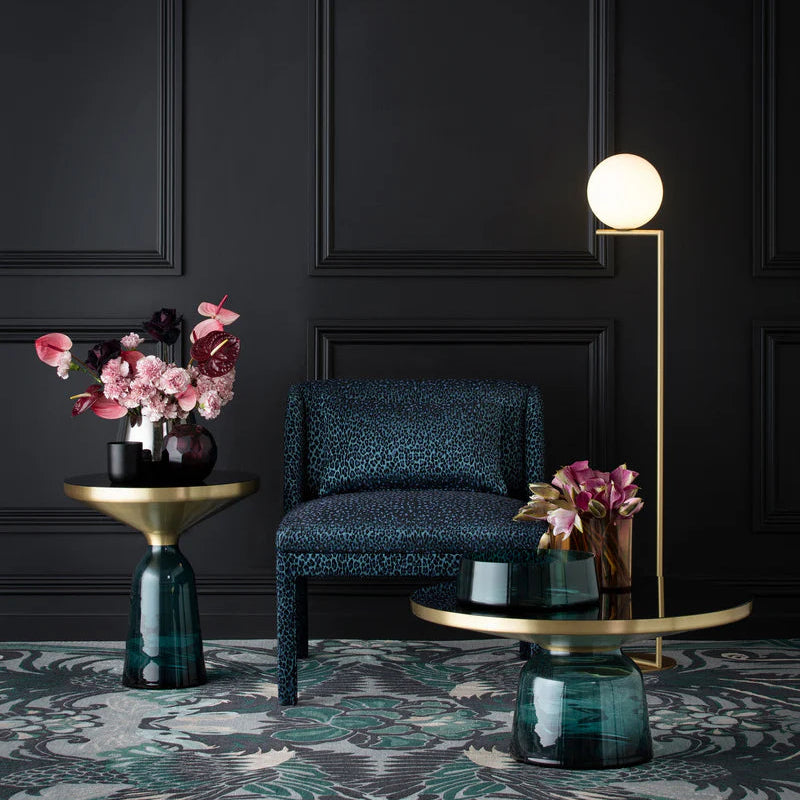 Modern interior with dark walls, a blue chair, and decorative tables with flowers.