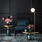 Modern interior with dark walls, a blue chair, and decorative tables with flowers.