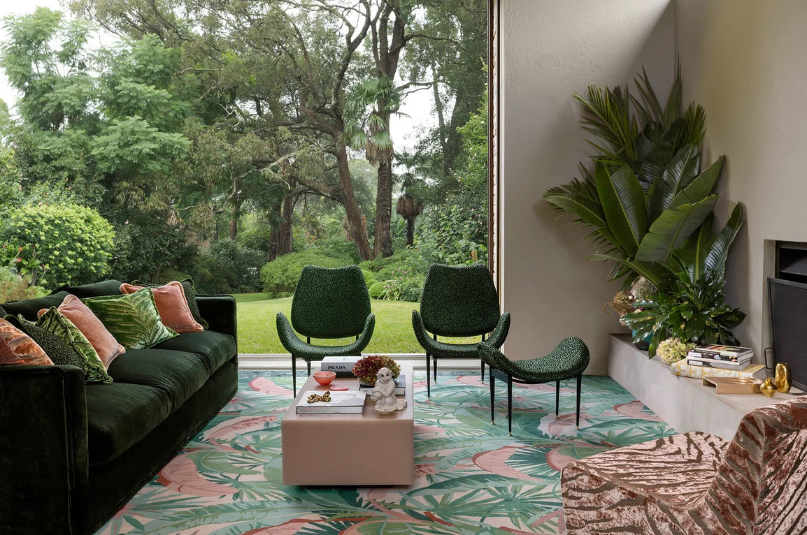 Modern living room with green sofas, chairs, and a colorful rug.