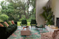 Modern living room with green sofas, chairs, and a colorful rug.