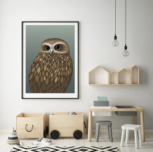Morpork owl picture in a black frame in a kids room with wood boxes on wheels and a pale wooden play desigk wiiht grey and white stools. ON the way are some wooden outlines of homes with two lightbulbs hanging from a black cord
