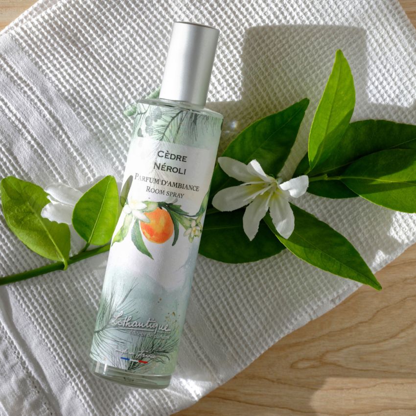 Room spray bottle with green leaves and white flower on a white cloth