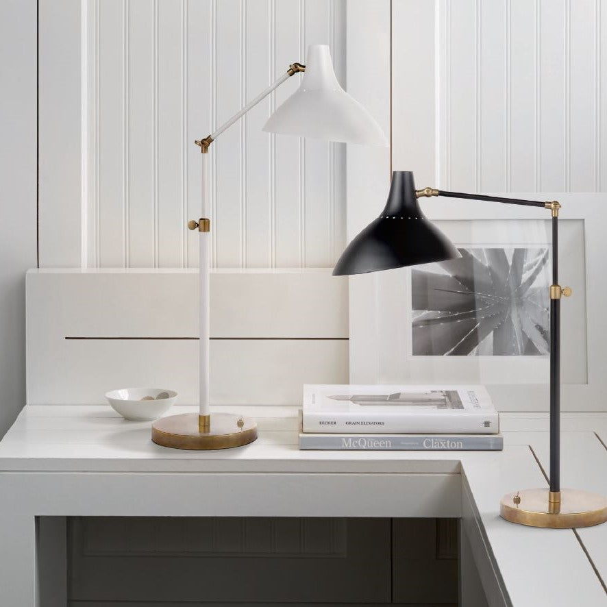 Carlton table lamp in black and white sitting on a white wooden table with white wooden walls and books on the desk