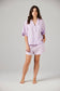 Woman wearing a light purple pajama set on a plain background