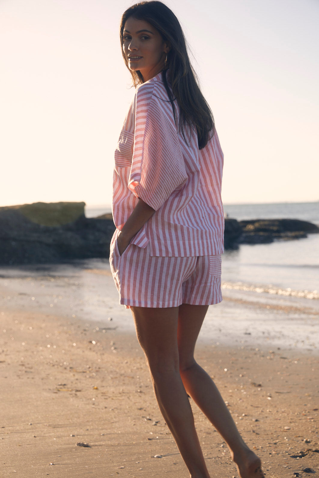 Woman in a striped outfit walking on a beach