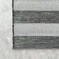 Close-up of a black and white striped rug on a concrete floor