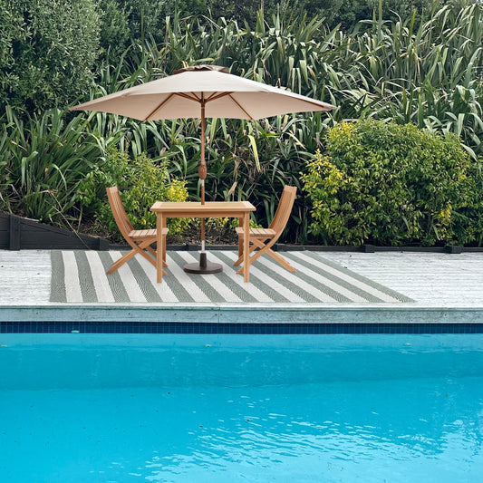 Outdoor setting with a table, chairs, and umbrella by a poolside.