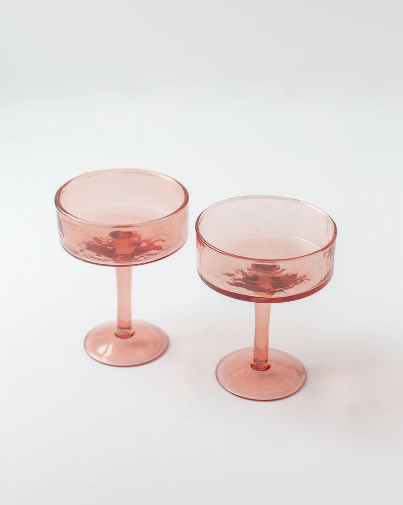Two pink cocktail glasses on a white background