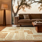 A modern living room scene featuring a large cream and brown patterned area rug under a brown fabric sofa, with a wooden floor lamp and coffee table.