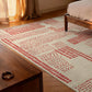 Patterned rug on a wooden floor with a bed and curtain in the background