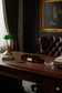 Vintage office desk with a green lamp, leather chair, and framed portrait.