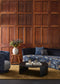 Modern living room with wooden paneled wall, blue sofa, and round coffee table.