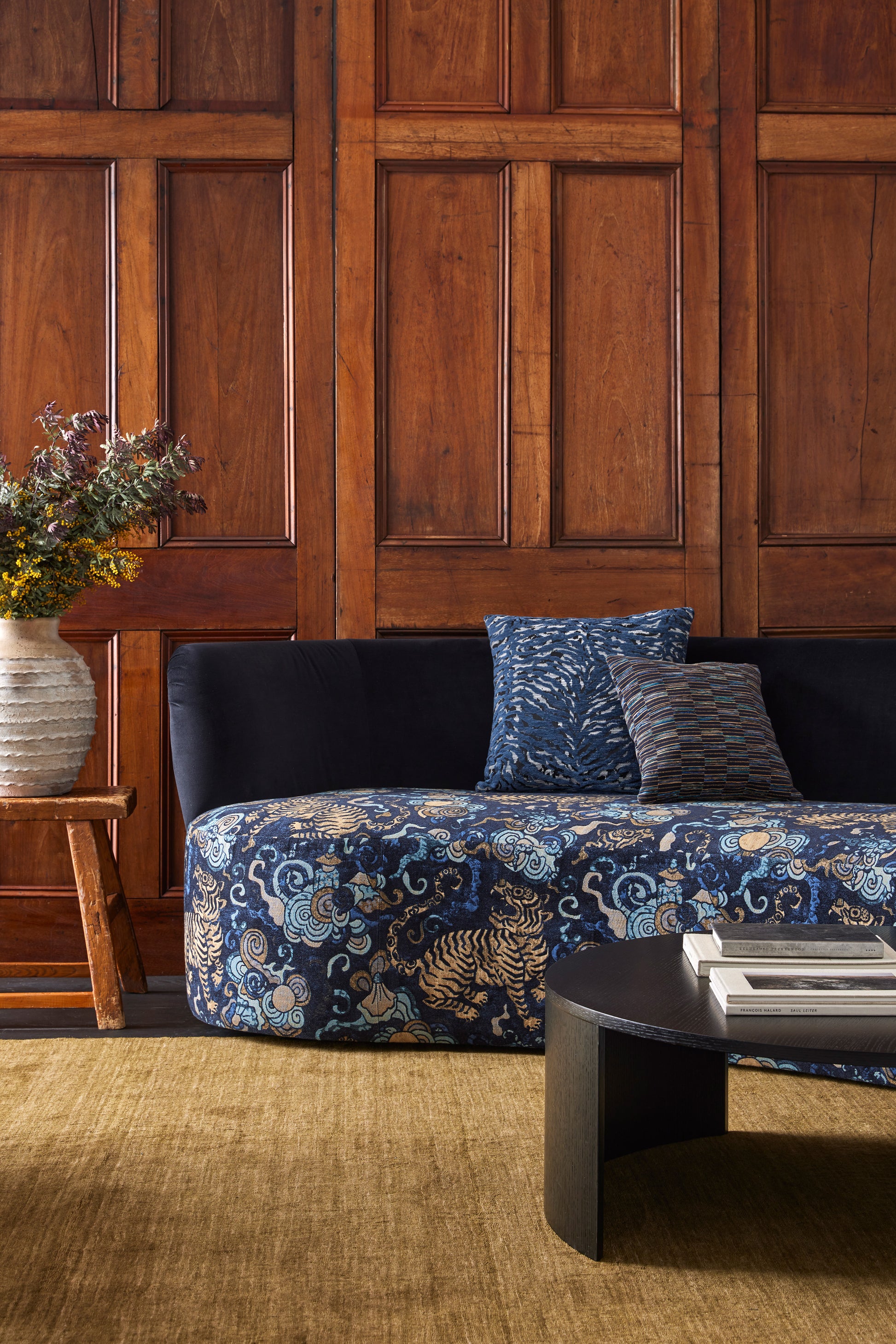 Sofa with blue floral pattern in a room with wooden paneling.