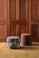 Two patterned stools against a wooden paneled wall.