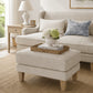 beige ottoman and sofa in hamptons style lounge with natural sisal rug, wooden coffee table and white accents like a lamp and vase