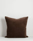 Brown pillow with decorative trim on a white background