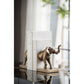Decorative elephant bookends on a reflective surface with a blurred background