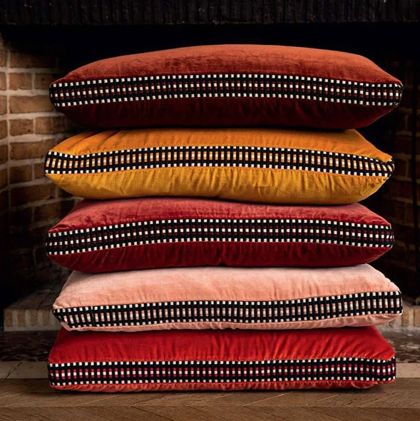 Stack of 5 Athena cushions by a fireplace