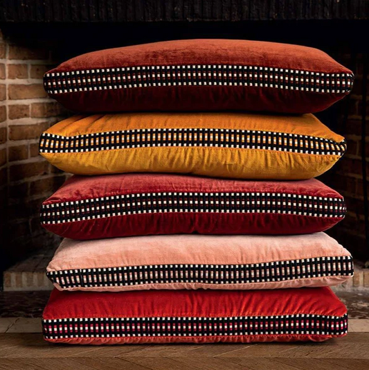 Stack of 5 Athena cushions by a fireplace