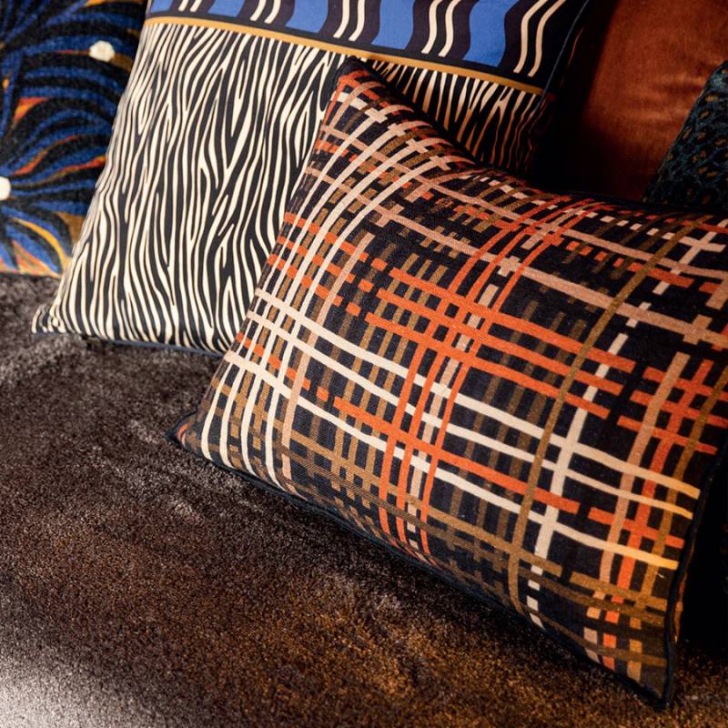 brown and orange striped oblong cushion in the foreground of a brown sofa. Animal print cushions are in the background