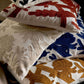 Pile of linen cushions embroidered with large florals and seed heads in blue, mustard, rust and beige