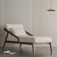 Modern chaise with wooden frame and white cushion in a minimalistic room.