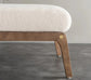 Close-up of a bench with wooden legs and a white cushioned seat on a gray floor.