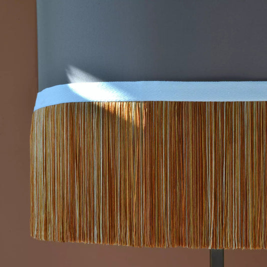 Close-up of a lamp with a wooden shade and metallic base against a brown background