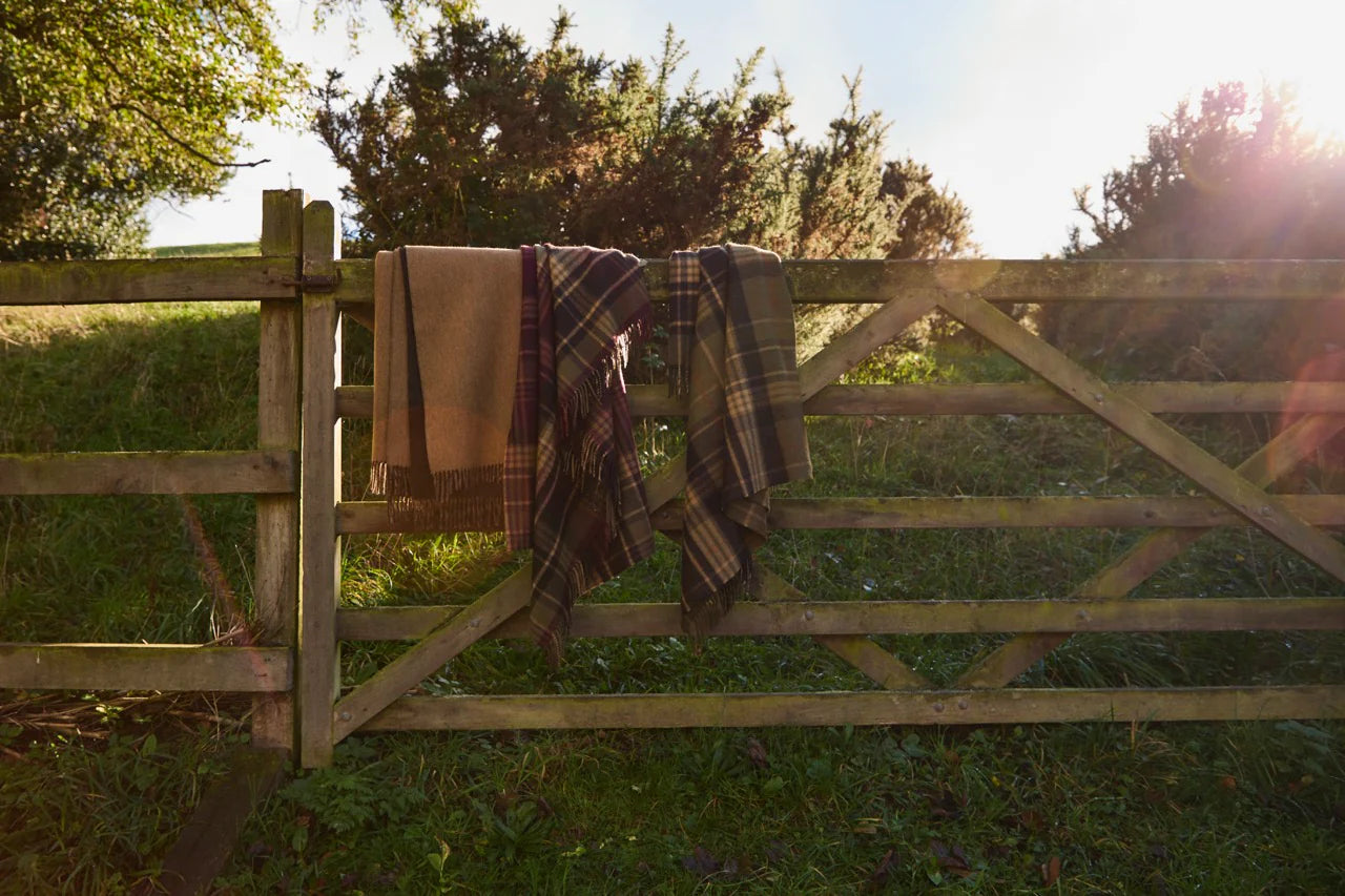 Plaid blankets hanging on a wooden gate with a natural background