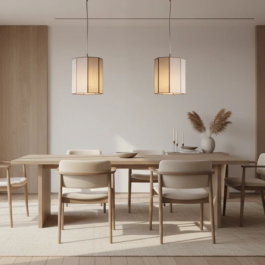 2 glass and bronze faceted pendants hanging above a pale wood dining setting in a modern room