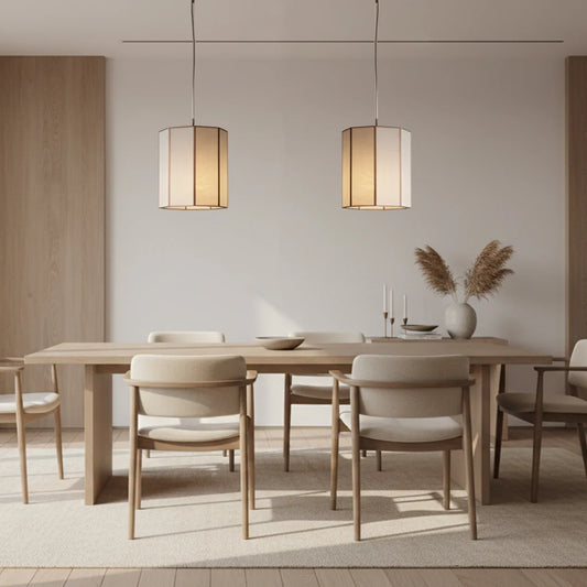 2 glass and bronze faceted pendants hanging above a pale wood dining setting in a modern room