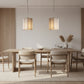 2 glass and bronze faceted pendants hanging above a pale wood dining setting in a modern room