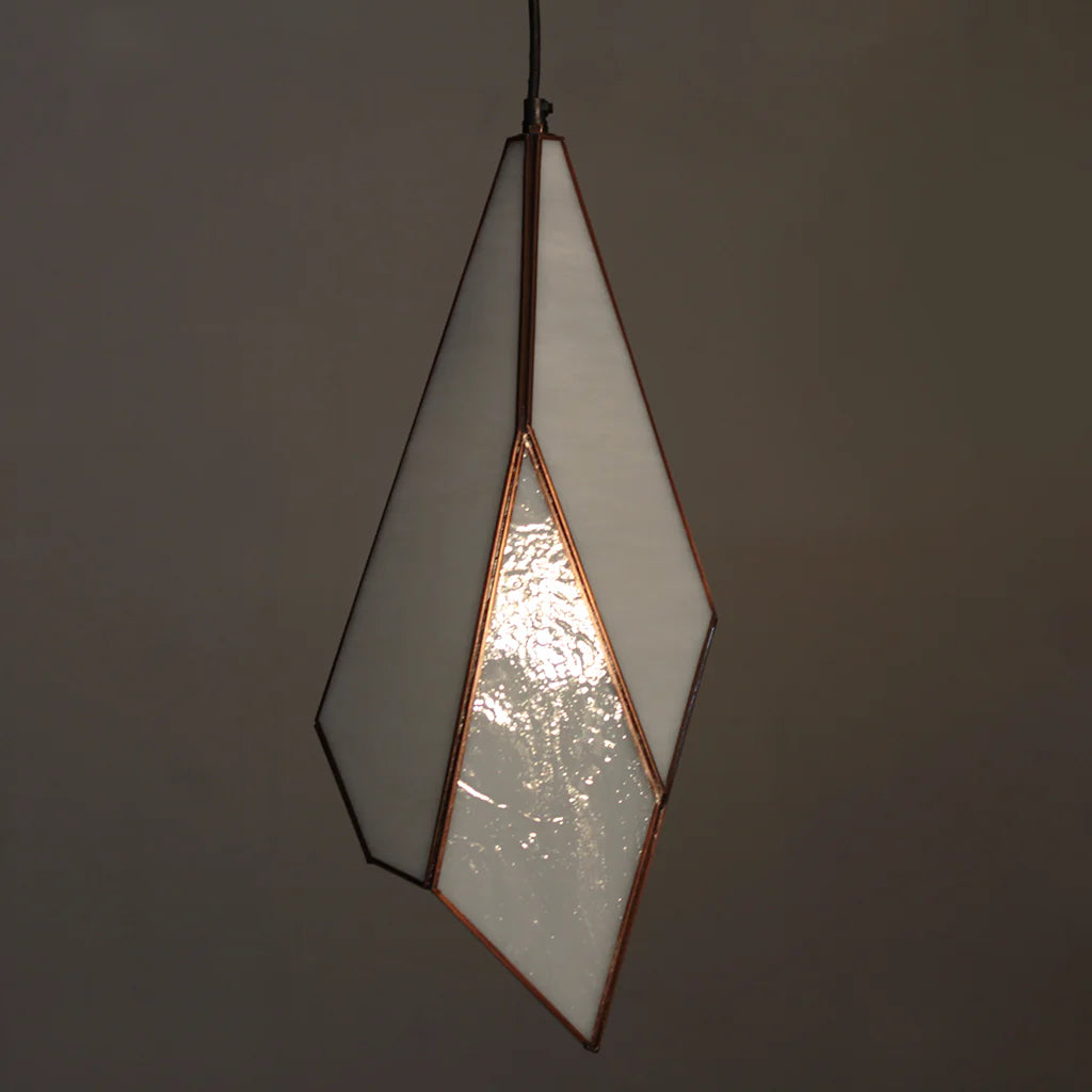 Geometric pendant light with a white glass shade and copper frame on a dark background