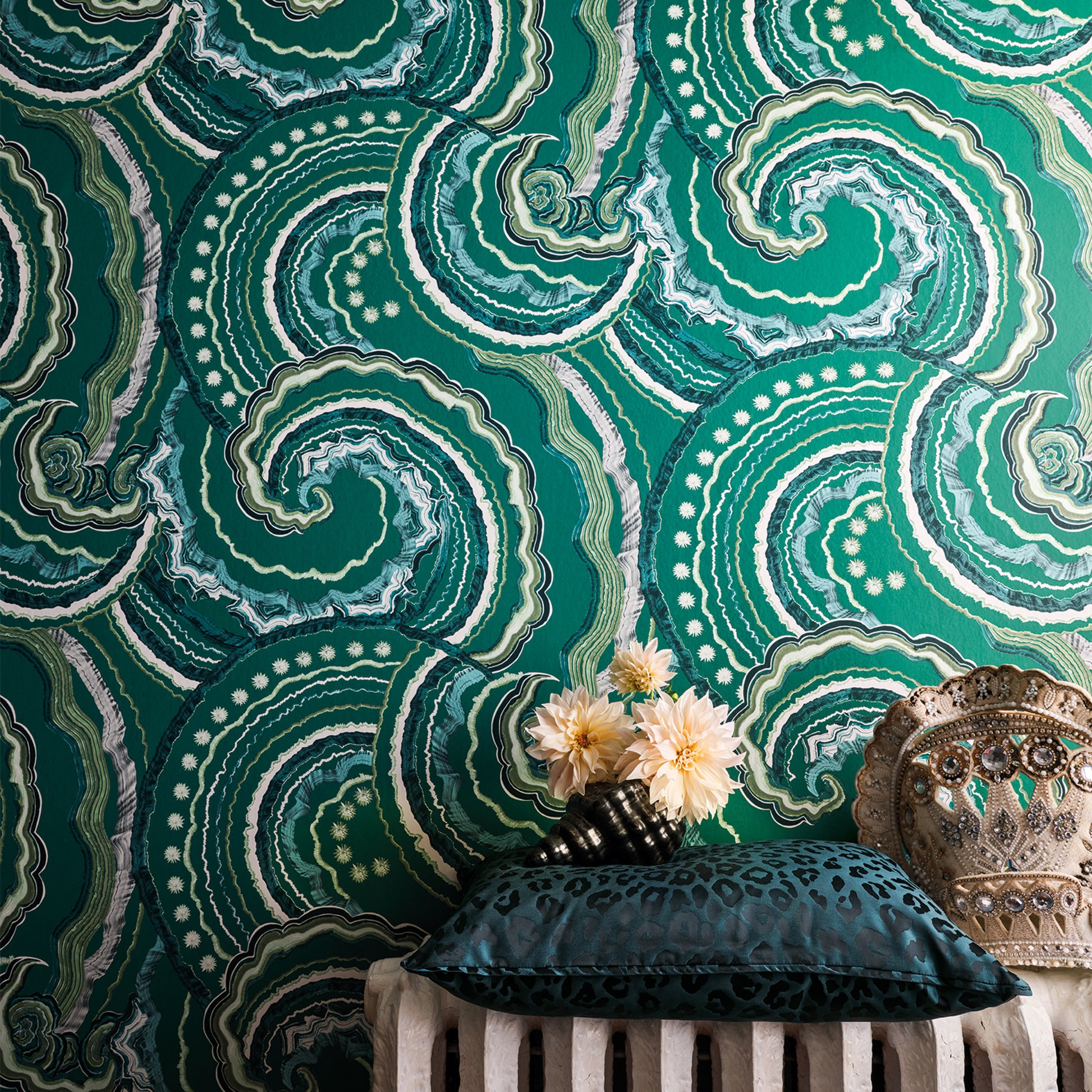 Decorative pillow on a chair against a green patterned wall.