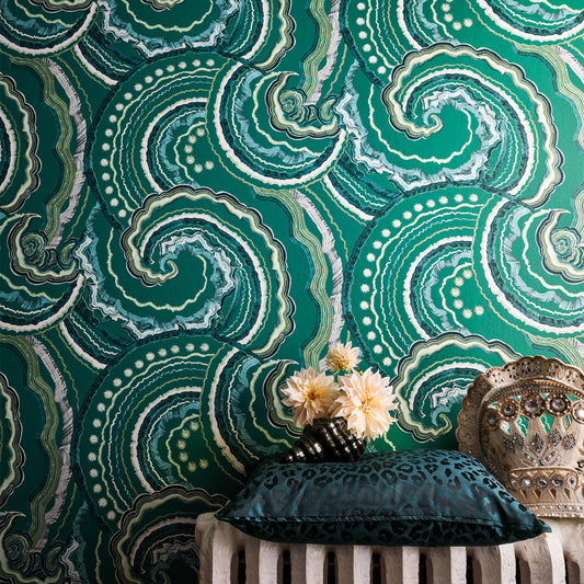 Decorative pillow on a chair against a green patterned wall.