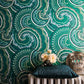 Decorative pillow on a chair against a green patterned wall.