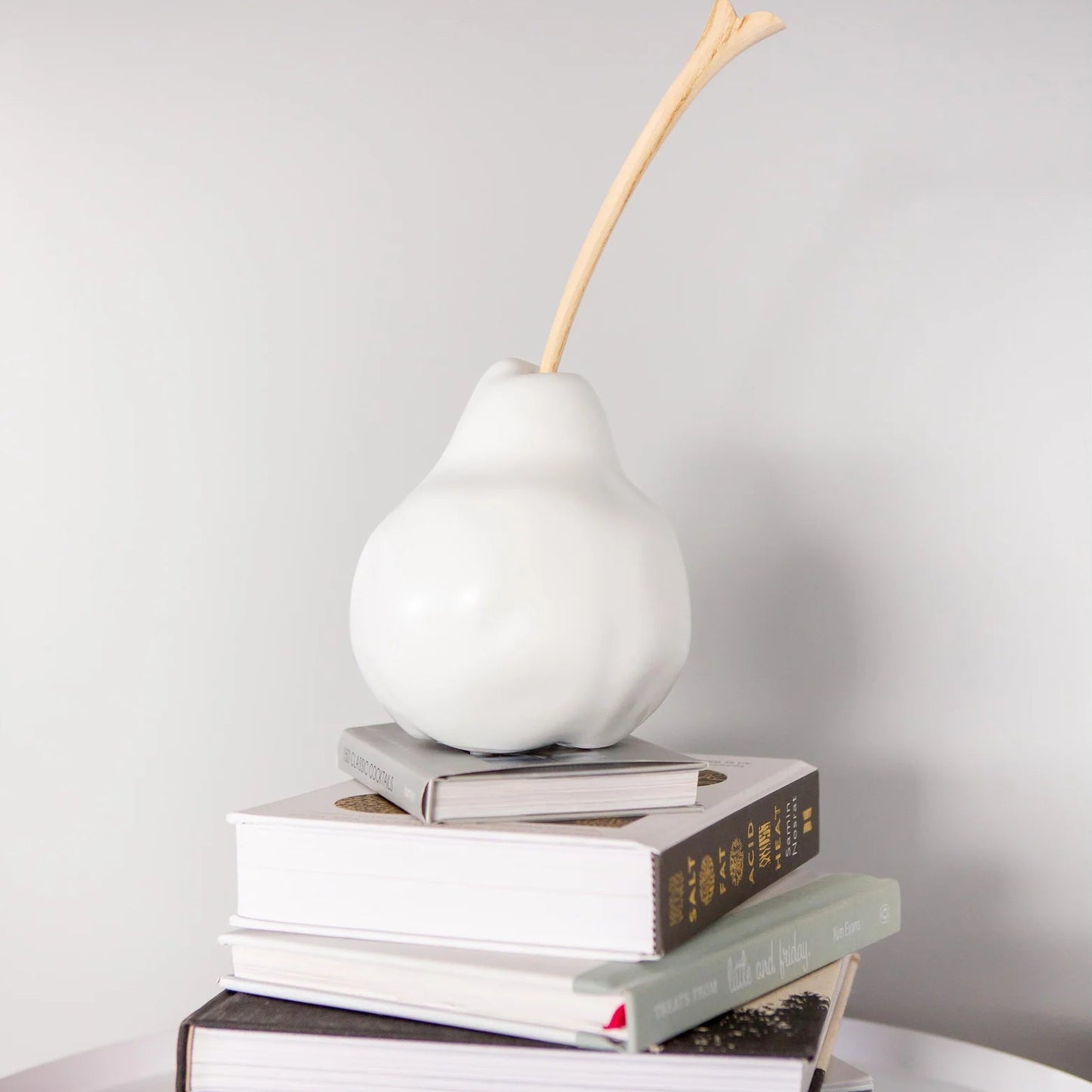 white decorative pear with wooden stem on pile of books