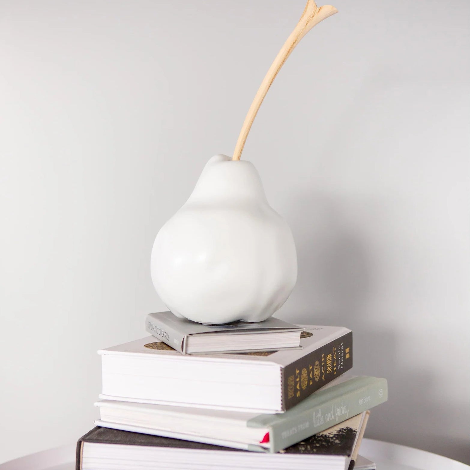 white decorative pear with wooden stem on pile of books