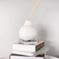 white decorative pear with wooden stem on pile of books
