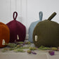Colorful felt doorstops with tags on a white surface with flowers.