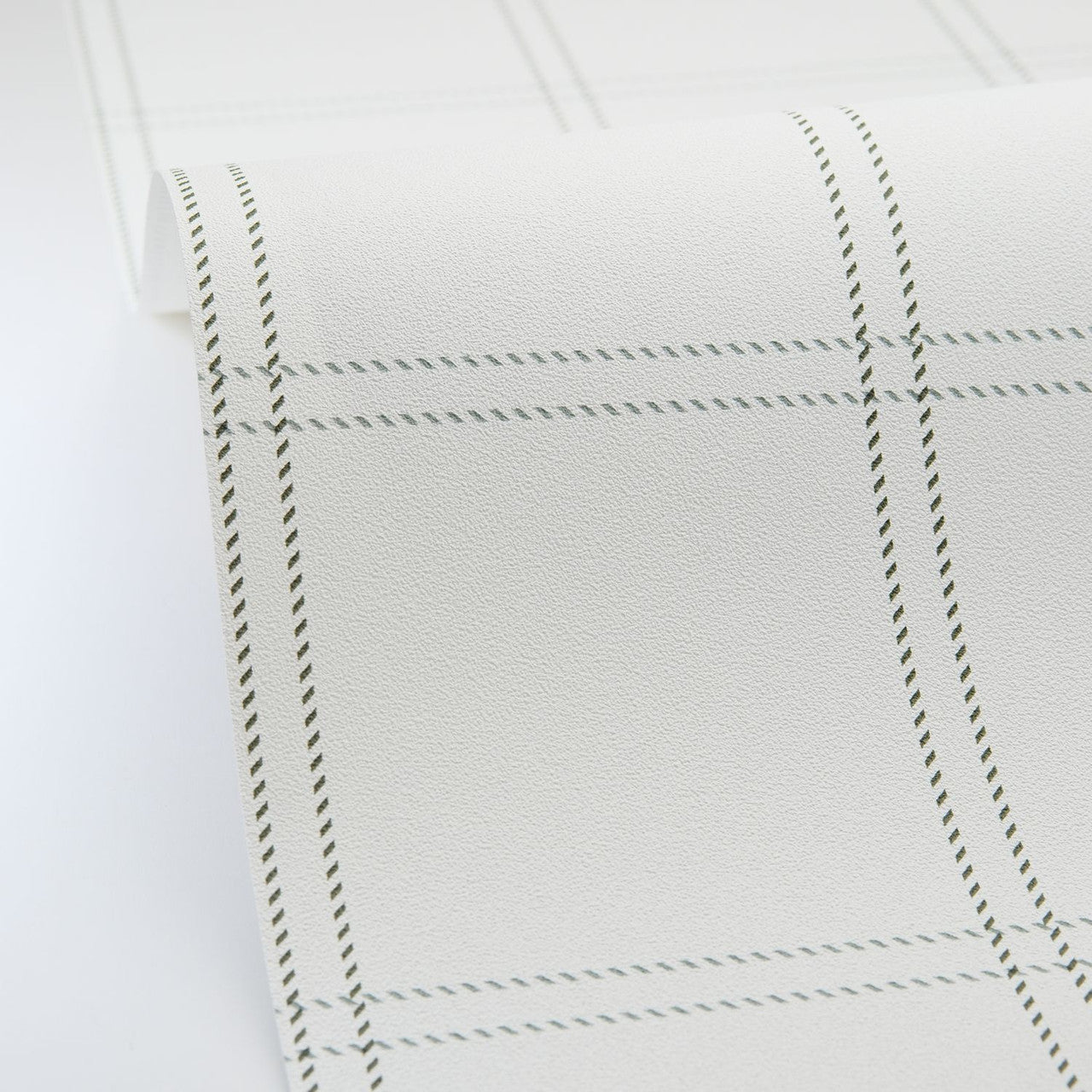Close-up of a white fabric with black stitching on a white background